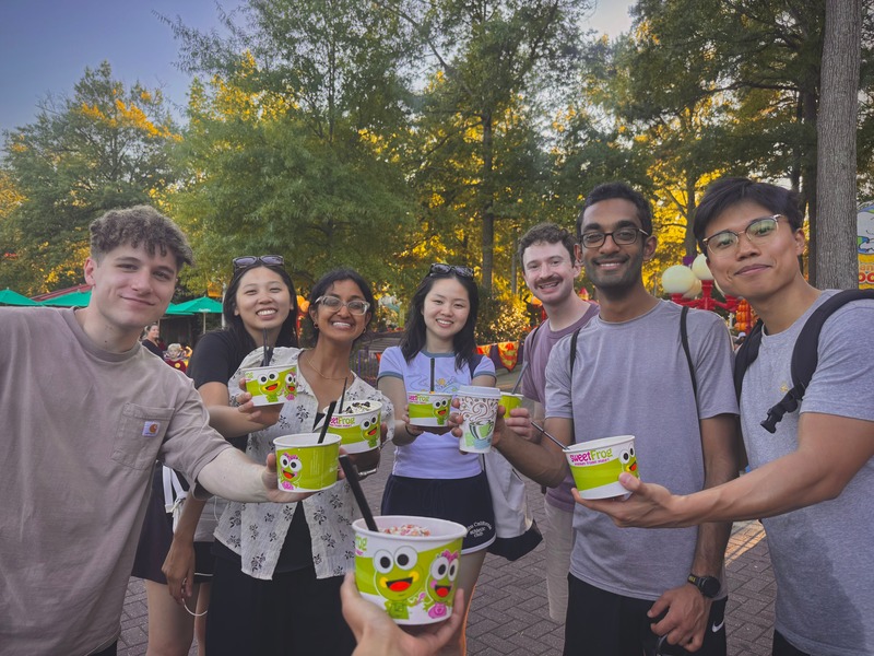 A group holding colorful snack buckets in a sunlit park.